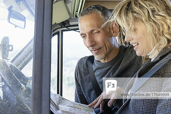 Mature couple looking at map and talking inside camper van on weekend travel