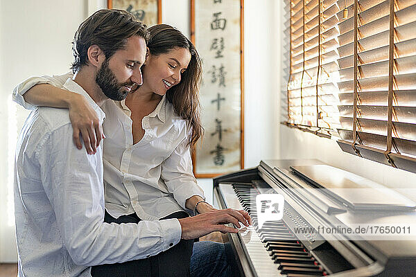 Couple playing piano sitting next to each other