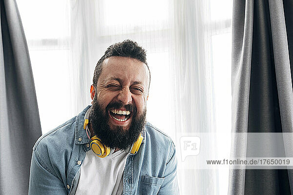 Hipster man with headphones laughing at home