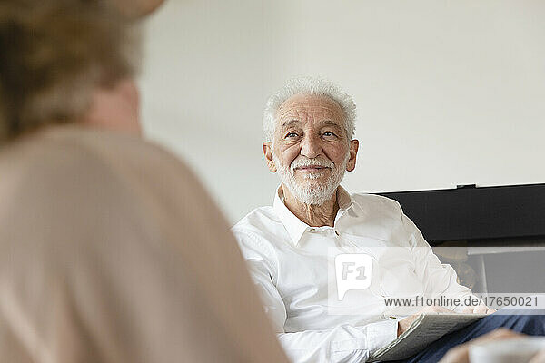 Lächelnder älterer Mann blickt Frau im Wohnzimmer an