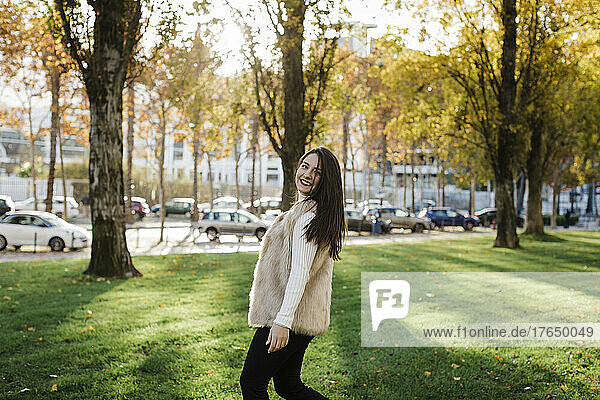 Glückliche junge Frau  die an einem sonnigen Tag im öffentlichen Park genießt