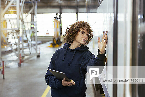 Engineer holding tablet PC analyzing monorail in factory