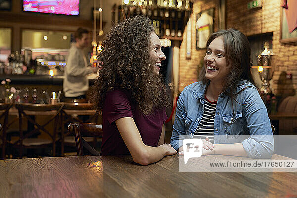 Two female friends talking in a pub