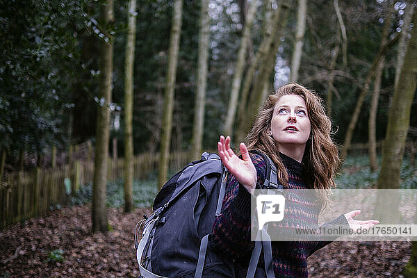 Frau mit Wanderrucksack gestikuliert im Wald
