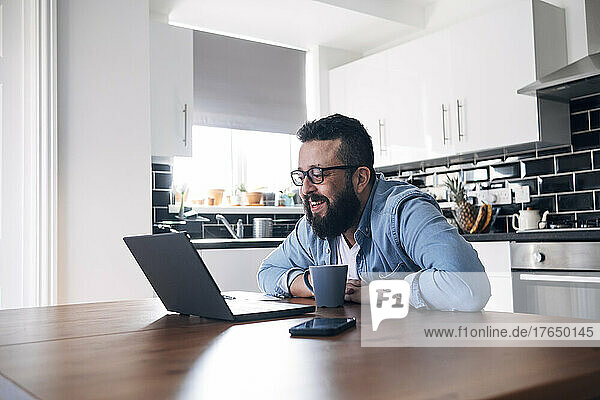 Lächelnder Freiberufler mit Laptop  der zu Hause arbeitet