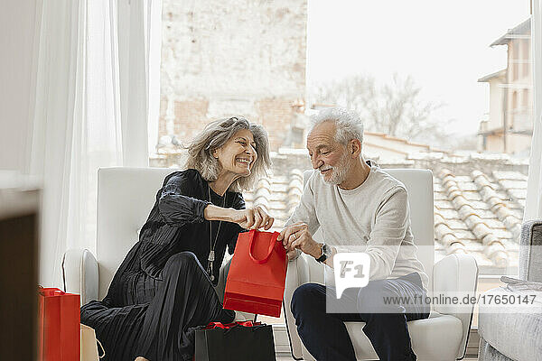 Smiling senior couple with shopping bags sitting at boutique hotel