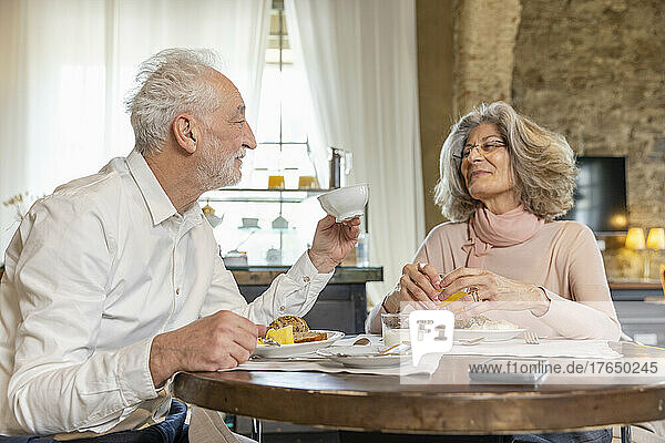 Senior couple having breakfast at table in boutique hotel