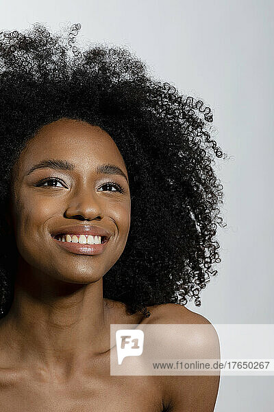 Smiling young woman with curly hair against white background