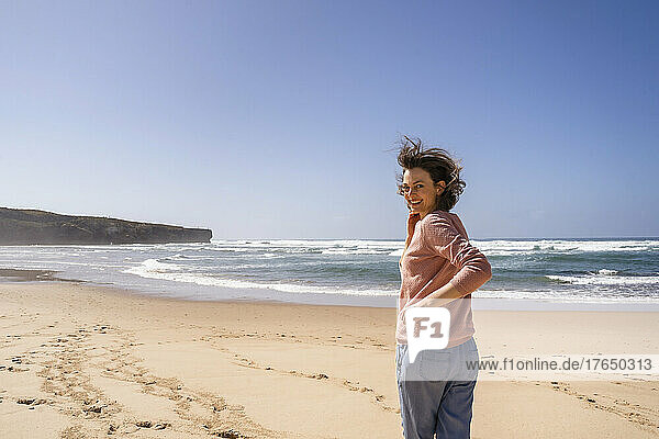 Glückliche Frau  die an einem sonnigen Tag am Strand in Richtung Meer rennt