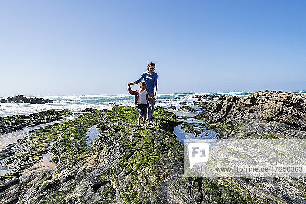 Mother and daughter walking on rocky beach