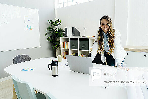 Smiling businesswoman with laptop at desk