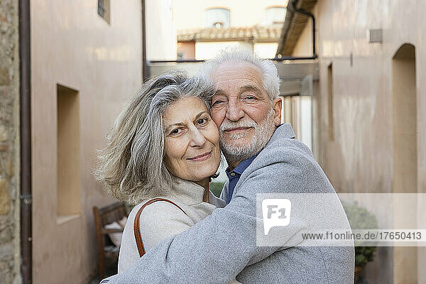 Glückliches älteres Paar  das sich im Innenhof des Hotels umarmt