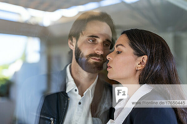 Couple separated through glass pane looking at each other