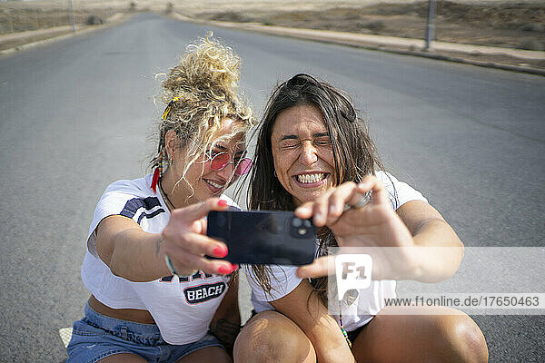Happy friends taking selfie through smart phone on sunny day