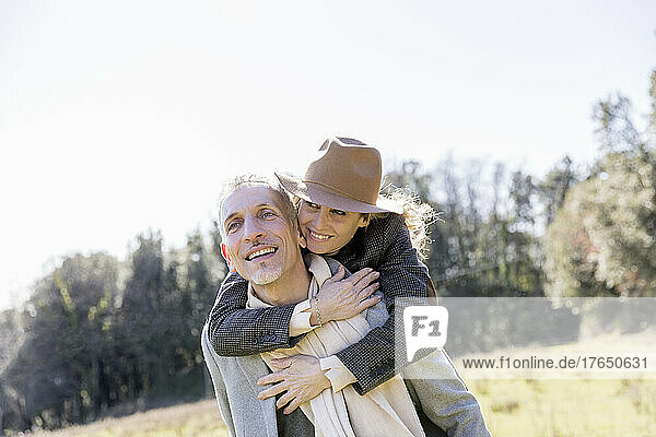 Happy man carrying woman piggyback on weekend