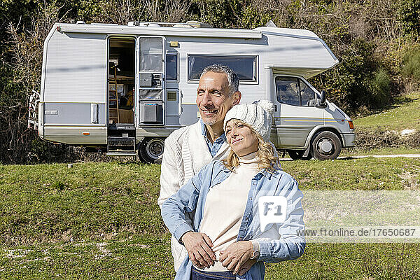 Mature couple embracing in front of their camper van on vacation