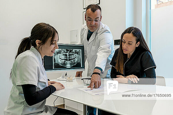 Dentist discussing medical report with nurses at desk in clinic