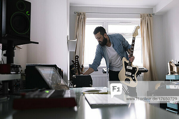 Freelancer with guitar using amplifier in home studio
