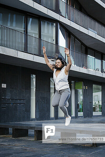 Woman jumping in front of building exterior