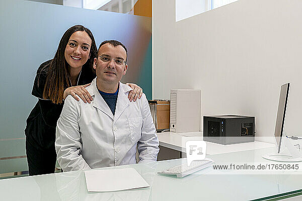 Confident doctor with nurse at desk in medical clinic