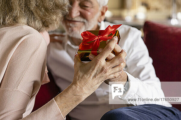 Senior man and woman holding gift at boutique hotel