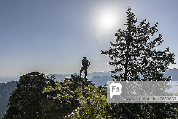 Germany  Bavaria  Sun shining over silhouette of male hiker standing alone at mountaintop