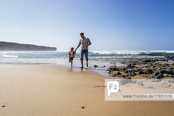 Happy father and daughter enjoying at beach on sunny day