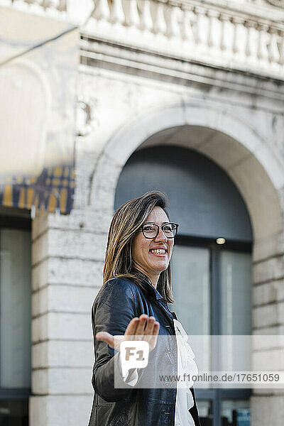 Smiling woman gesturing standing in city
