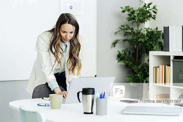 Businesswoman using laptop at desk in office