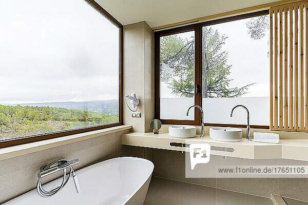 Bathtub by window in modern luxury bathroom at hotel