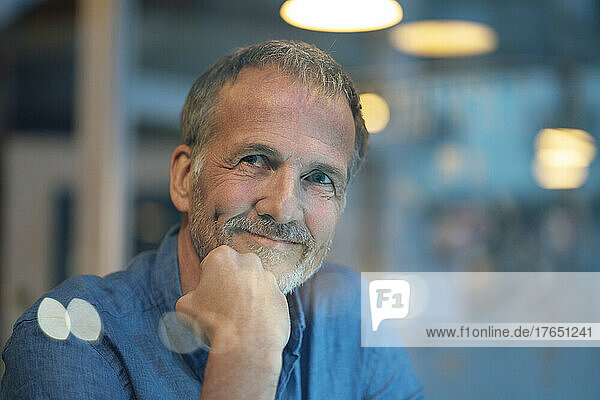Contemplative businessman with hand on chin sitting at cafe