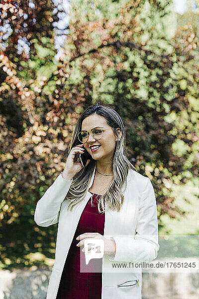 Happy businesswoman talking on mobile phone at park