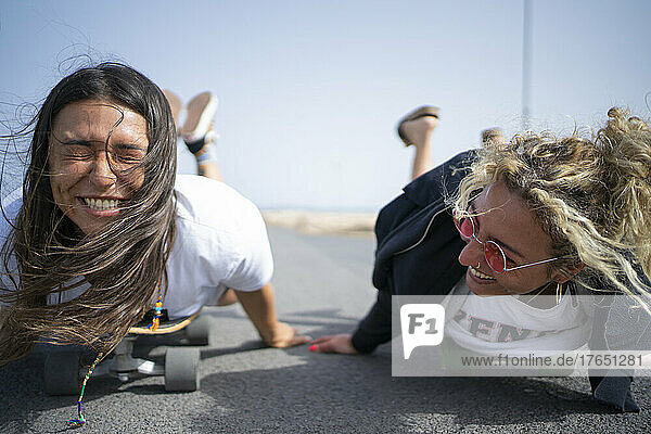 Friends having fun by lying on front on skateboard