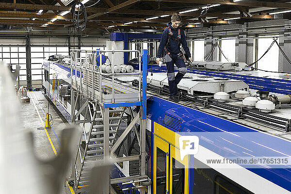 Engineer walking on monorail rooftop in factory