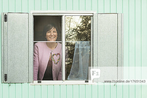 Lächelnde Frau  die vom Wohnwagen aus durch das Fenster schaut