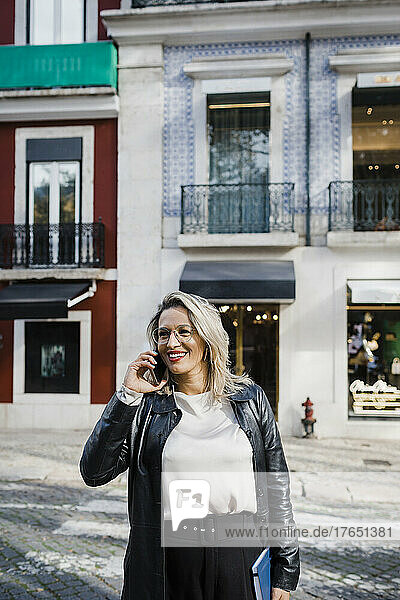 Lächelnde Frau  die auf der Straße über ihr Mobiltelefon spricht