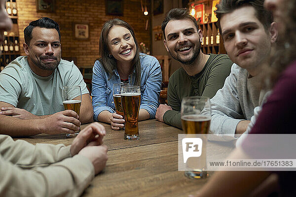 Group of friends having beer and socializing in a pub