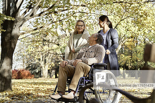 Smiling disabled man with nurse looking at senior woman talking at park