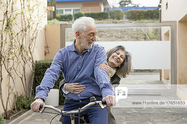 Glückliche ältere Frau  die mit einem Mann sitzt  der Fahrrad fährt