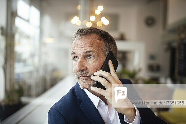 Senior businessman talking on mobile phone in cafe