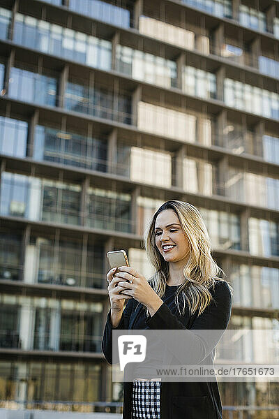 Smiling businesswoman text messaging on mobile phone