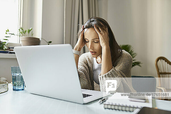Stressed freelancer sitting with laptop at desk