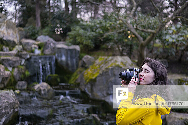 Young woman photographing with camera in forest