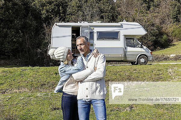 Woman embracing man in front of camper van