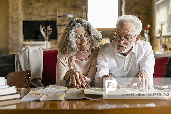 Lächelnde Frau und Mann  die auf dem Sofa im Boutique-Hotel sitzen und auf den Stadtplan schauen