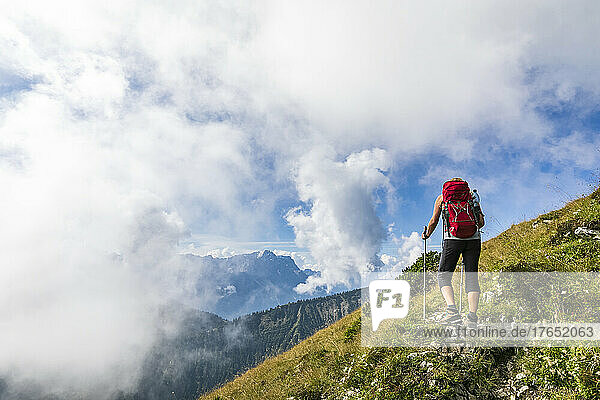 Woman with hiking pole walking on mountain