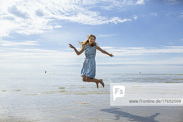 Mädchen springt an einem sonnigen Tag am Strand