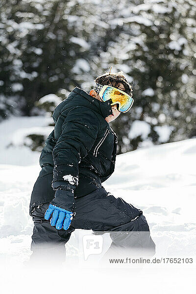 Boy wearing ski goggles walking in snow
