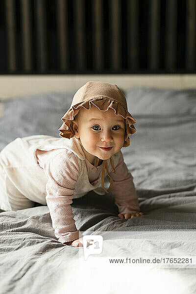 Smiling baby girl crawling on bed at home