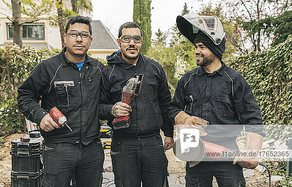 Happy workers with grinders and work tools at construction site